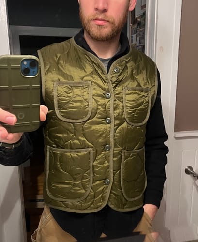 Reviewer showing the snug fit of the olive Military Style Quilted Padded Vest.