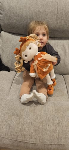Customer's photo of a child sitting on a couch and hugging the Personalized Reindeer Girl doll.