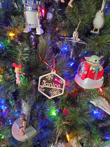 Reviewer's personalized wooden ornament with 'Janice' and snowflakes hanging on a Christmas tree.