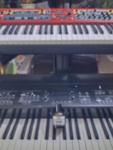 Recensore mostra il suo profumo VESEVO su una tastiera musicale in questa immagine sfocata.