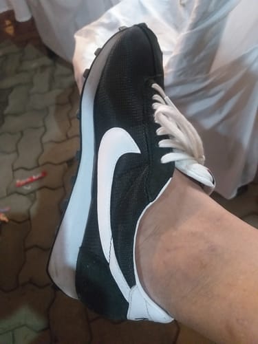 A reviewer's foot wearing the black Nike LD-1000 shoe with a white swoosh and sole.