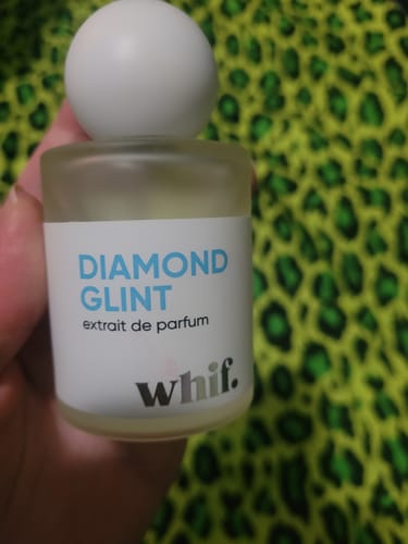 Customer holding the frosted glass bottle of Diamond Glint perfume, showing the white cap and label.