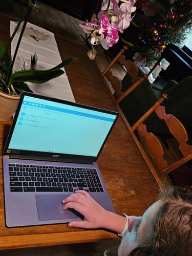 Close-up of a reviewer using the Time4Learning Fourth Grade Curriculum on a laptop at a wooden desk.
