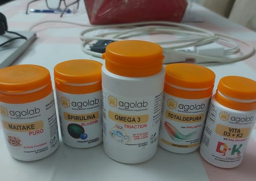 Recensore mostra il flacone di Maitake Puro con altri integratori Agolab su un tavolo.