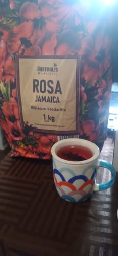 Un reseñador muestra su bolsa de 1 kg de Rosa Jamaica junto a una taza que contiene la infusión roja.