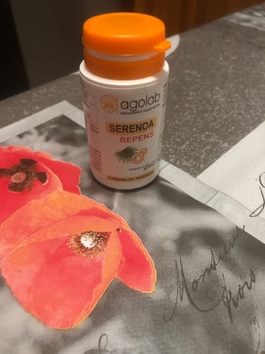 Il recensore mostra il flacone bianco di Serenoa Repens con il tappo arancione, appoggiato su un tavolo.