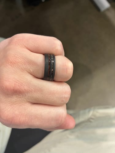 Close-up of a customer wearing a dark Thorum Replacement ring with a wood and speckled silver inlay on their finger.