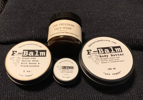 Customer's jar of The Freedom Face Whip shown with a collection of F-Balm tins on a dark fabric.
