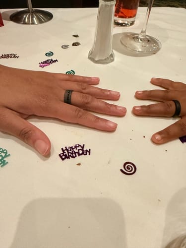 Customer showing a Black Meteorite ring on an adult's hand and a matching one on a child's hand over a table.