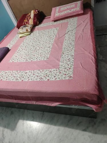 Customer's Flo Mattress Ortho on a bed, covered with a pink floral bedsheet and matching pillows.