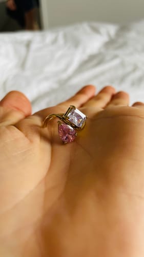 Customer holding the Navae Birthstone Ring in their palm, showing the pink and clear stones on the gold band.
