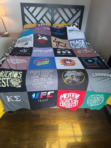 Customer's custom Premium T Shirt Quilt spread out on a bed, showing the patchwork of different t-shirts.