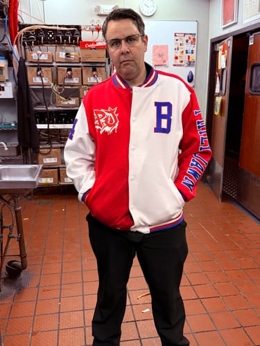 Reviewer from the front in a custom red and white split varsity jacket with a logo and the letter 'B' on the chest.