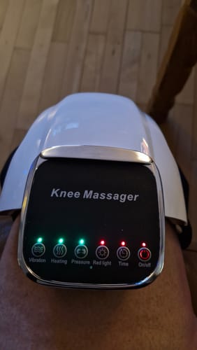 Anmelders ComfortKnee™ massageapparat på knæet, hvor man ser det oplyste kontrolpanel, der viser indstillingerne.