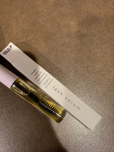 Customer's Lash Serum tube with golden liquid and spoolie applicator next to its white box.