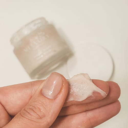 Close-up of a customer showing the creamy, beaded texture of the Dragonfruit Face Scrub on their finger.