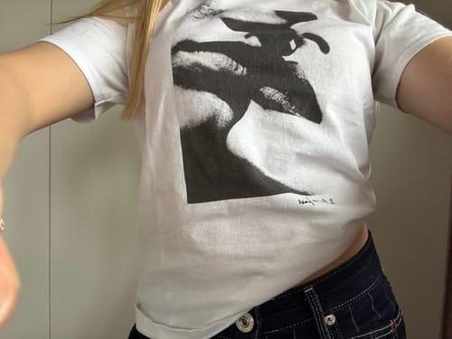 Reviewer showing the fit of their white love or lust baby tee in a close-up photo.