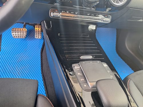 Recenzent pokazuje niebieskie dywaniki samochodowe zamontowane z przodu pojazdu.