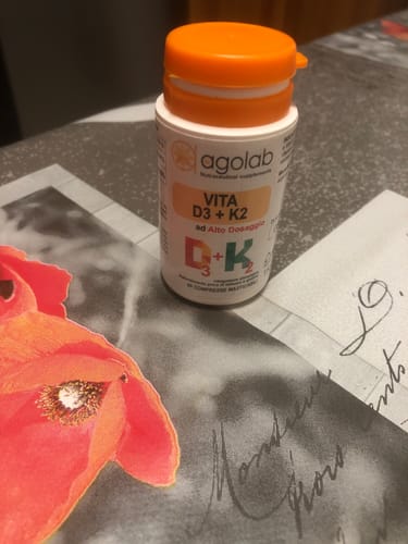 Il flacone di Vitamina D3 + K2 Masticabile del recensore, con tappo arancione, su un tavolo.