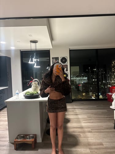 Reviewer in a mirror selfie showing the very short fit of the Faux Fur Leopard Mini Skirt and matching top.