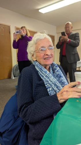Reviewer's mother, who the review says uses Emma, smiling while sitting at a table.