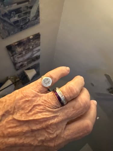 Close-up of a reviewer's hand wearing the Guardian 6mm ring with its rose gold band and purple inlay.