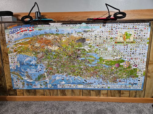Customer's large, detailed World's Greatest Search & Discover poster mounted on a wood-paneled wall.