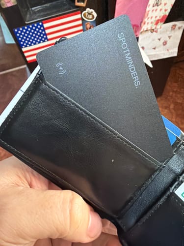 Reviewer sliding the black SPOTMINDERS Tracking Card into a wallet slot.