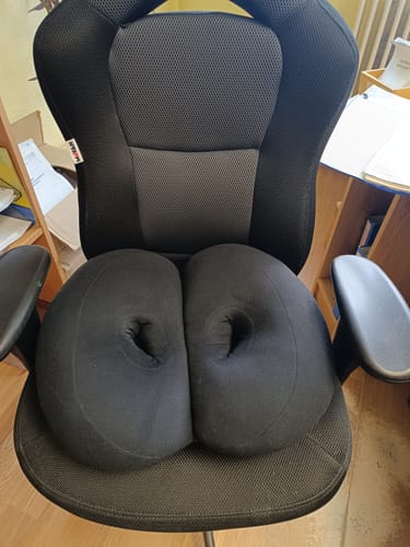 A vásárló fekete Comfy Gerinctámogató Ortopéd Ülőpárnája egy irodai széken látható.