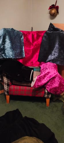 Customer's crushed velvet fabric samples in fuchsia, blue, and black draped over a plaid armchair.