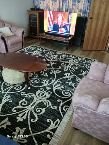 Customer's large, traditional patterned rug placed on a wooden floor in a living room setting.