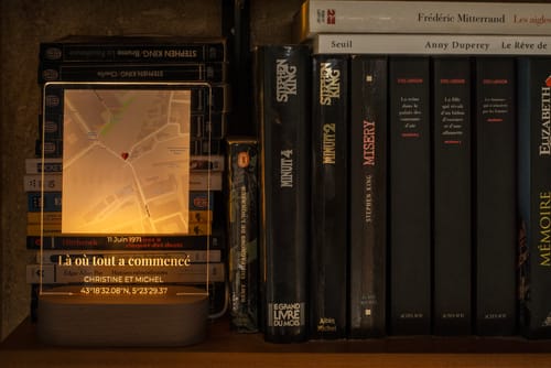 Ein Rezensent zeigt das personalisierte Nachtlicht „Notre Moment“, das auf einem Bücherregal warm leuchtet.