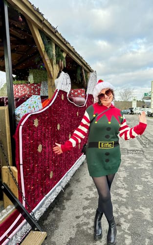 Reviewer in an elf costume stands by a trailer decorated with red Crushed Velvet Fabric.