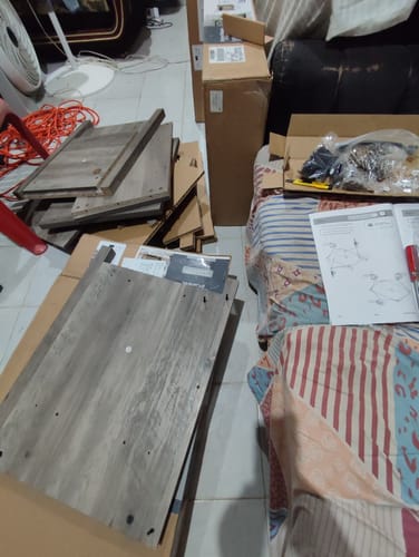 Cliente muestra las piezas de madera de la Mesa Auxiliar rústica antes de ensamblarla en su sala.