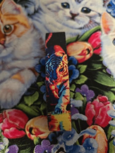 A reviewer's 'Never Back Down' bracelet from the Tiger Pack laid on a patterned surface, showing its colorful tiger design.
