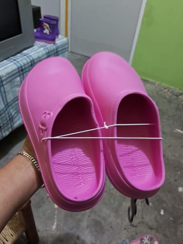 Cliente sosteniendo en su mano un par de zapatos rosita sin cordón.