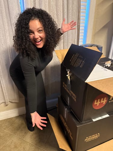 Reviewer excitedly posing with the large delivery boxes for their Quarter Beef Bundle.