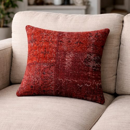Reviewer's red, distressed Hali Bursa cushion cover propped up on a light-colored sofa.