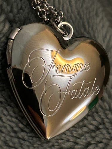 Customer's close-up of the shiny silver Femme Fatale Locket with 'Femme Fatale' engraving.