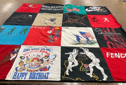 Customer's colorful Premium T-Shirt Quilt laid out, showcasing patches with fencing, birthday, and other personal graphics.