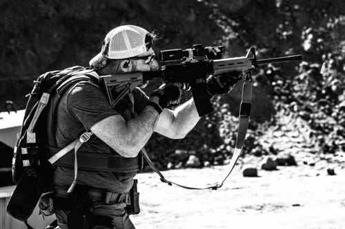 Reviewer firing a rifle outdoors while wearing the GS Extreme 2.0 for hearing protection.