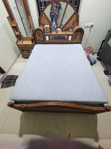 Reviewer's grey Flo Anti-Gravity™ Latex Mattress placed on an ornate wooden bed frame.