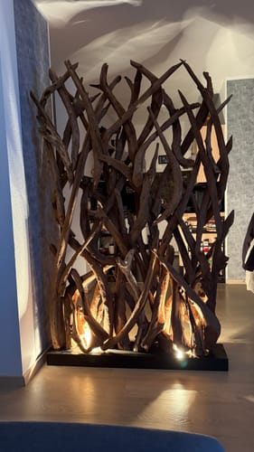 Kundenbild des beleuchteten Treibholz-Raumteilers in einer Zimmerecke. Die Spots im Sockel schaffen ein warmes, gemütliches Licht.