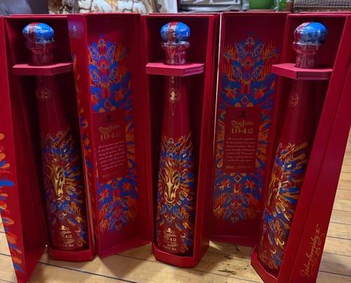 Reviewer showing three limited-edition Don Julio 1942 Year Of The Horse Tequila bottles in their open red presentation boxes.