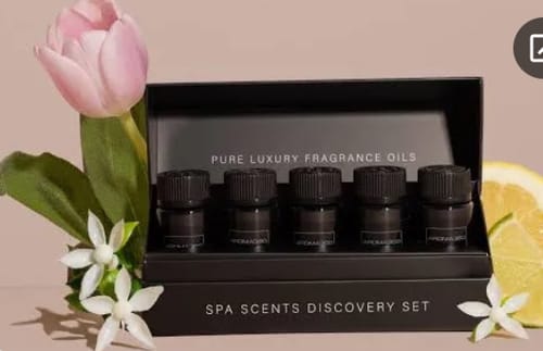 Customer's Aroma Oils Sample Box in its black packaging, styled with a pink tulip, white flowers, and a slice of lemon.