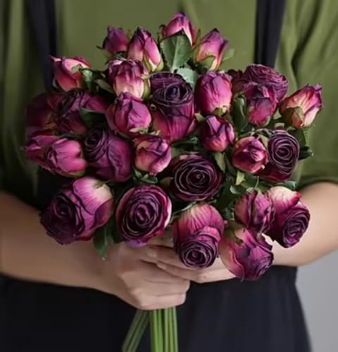 Reviewer holding a large bouquet of deep purple artificial flowers.