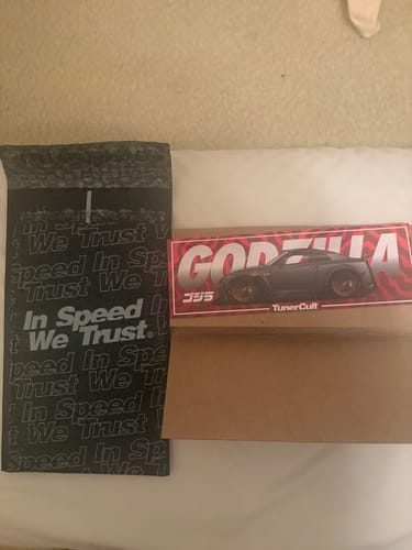 Customer's GODZILLA SLAP STICKER featuring a dark car, displayed with its original shipping mailer.