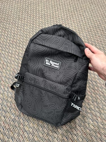 Customer holding their black PATHWAY backpack, which has a white topographic line pattern.