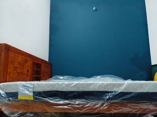 Customer's Flo Anti-Gravity™ Latex Mattress in its plastic wrap, placed on a wooden bed frame.