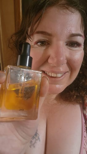 A smiling reviewer holds up her bottle of SEA BUCKTHORN SERUM to show her positive results.
